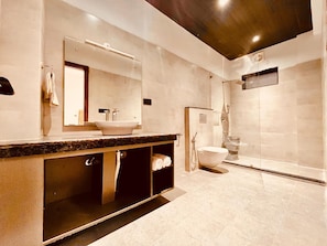A modern bathroom with a large mirror, a sink, a toilet, and a shower. - Hotel Aura Residency Haridwar  (Rishikesh)