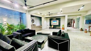 A spacious lobby with seating areas, a reception desk, and a TV screen.