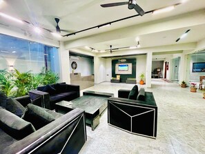 Eine großzügige Lobby mit Sitzbereichen, einem Empfangsbereich und einem Bildschirm.