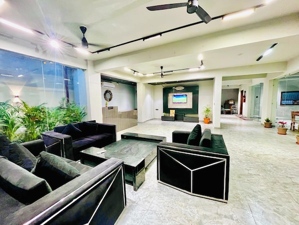 A spacious lobby with seating areas, a reception desk, and a TV screen.