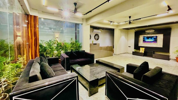 A modern reception area with a TV, seating, and plants.