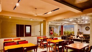 A restaurant with wooden tables and chairs, a large mirror, and a view of the outdoors.