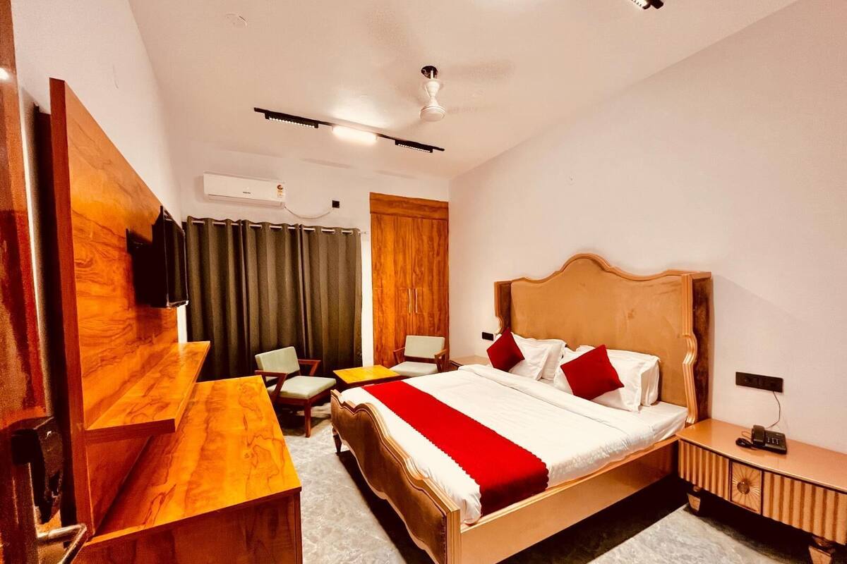 Habitación de hotel con cama, escritorio, silla, mesita, armario y ventilador de techo.