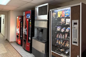 Una fila de máquinas expendedoras con aperitivos y bebidas, incluyendo Coca-Cola y Pepsi, en un entorno comercial.