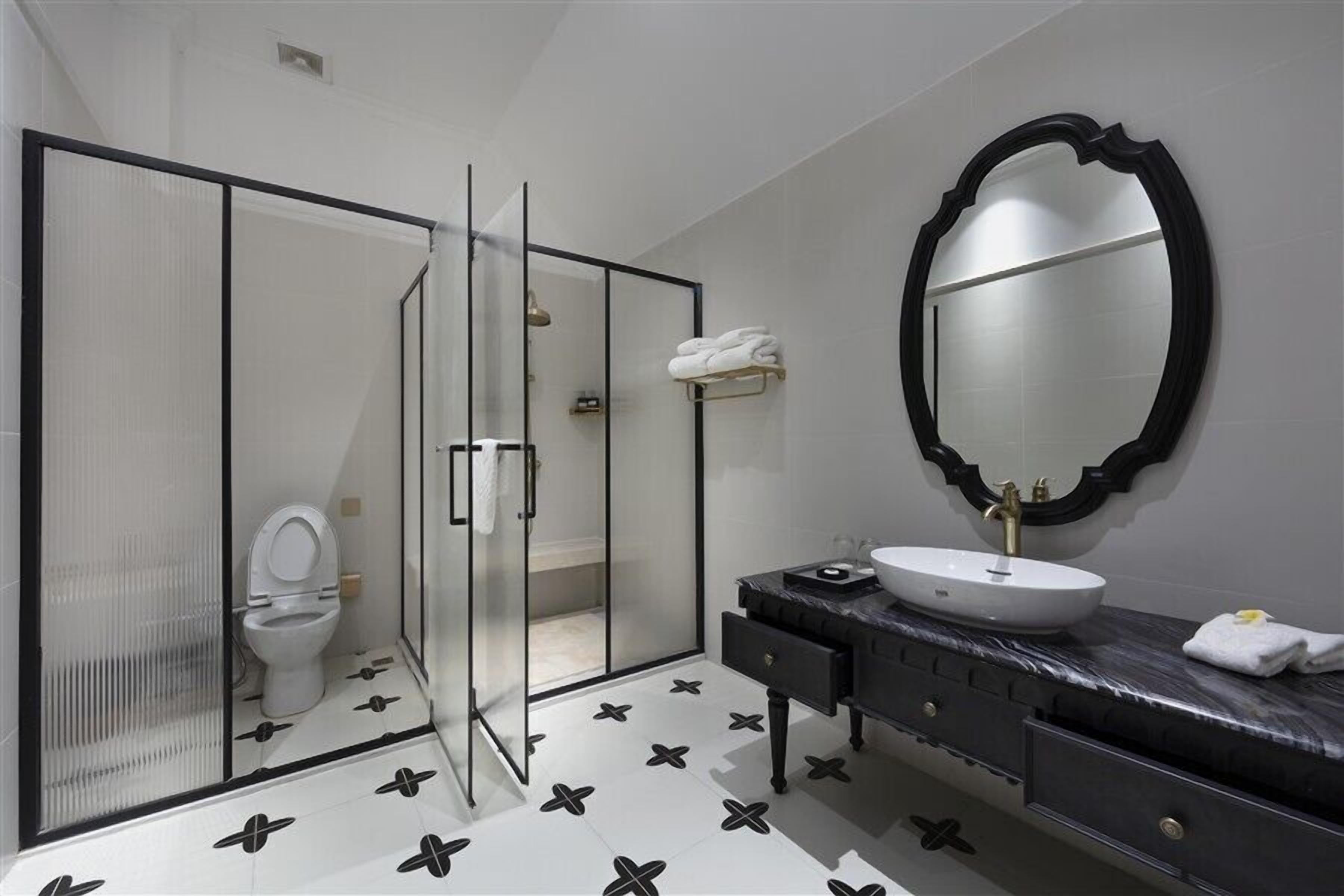 A modern bathroom with a glass-enclosed shower, a white sink, and a large mirror.