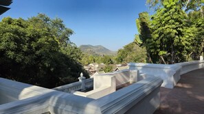 Eine Terrasse mit Blick auf ein Dorf, umgeben von Bäumen und einem Berg im Hintergrund.
