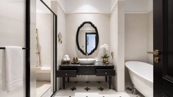A modern bathroom with a freestanding bathtub, a vanity with a large mirror, and a patterned floor.
