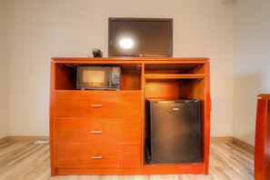 Eine kompakte Küchenzeile mit Mikrowelle, kleinem Kühlschrank und Fernseher darauf.