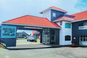 Ein neues Port Inn mit rotem Ziegeldach, einer überdachten Eingangspforte und einem sichtbaren Parkplatz.