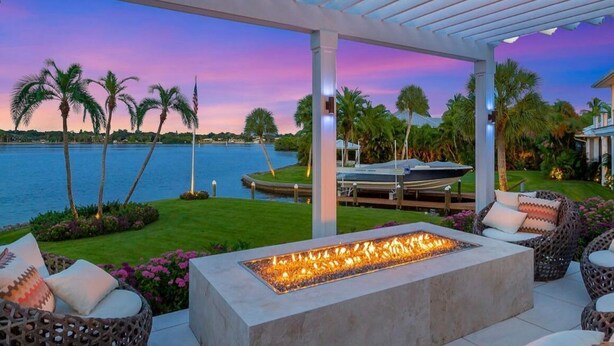 A covered outdoor seating area with a fire feature, a pool, and palm trees. - Casey Key Paradise~Private Beach~Gulf to Bay (Nokomis)