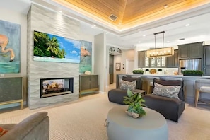 A modern living room with a fireplace, a television, and a kitchen area with dark cabinets. - Casey Key Paradise~Private Beach~Gulf to Bay (Nokomis)