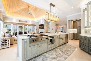 A spacious kitchen with a central island, built-in appliances, and a large window overlooking a scenic view. - Casey Key Luxe Paradise~Private Beach~Gulf to Bay (Nokomis)