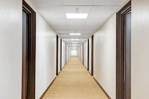 A long, narrow hallway with carpeted floors and white walls.