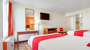 Een hotelkamer met twee bedden, een bureau met spiegel, een televisie, een verwarming en een raam met gordijnen.