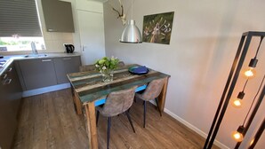 Una cocina con una mesa de madera, dos sillas, una lámpara colgante y un cuadro en la pared.