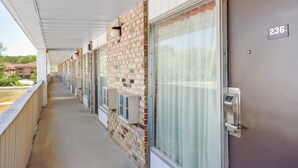 A hotel corridor with a brick wall, a covered walkway, and a door marked with the number 236.
