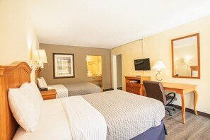 A hotel room with two beds, a desk, a chair, a television, and a mirror.
