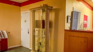 Un couloir avec une vitrine, une porte blanche et un mur rouge.