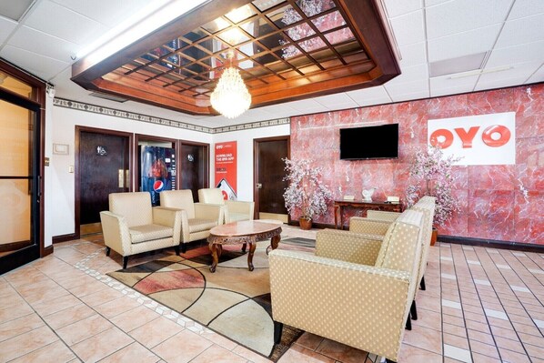 A lobby with seating, a chandelier, a wall-mounted TV, and a 'OYO' sign.