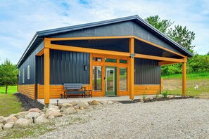 A modern building with a covered porch, a bench, and a door.
