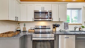 A modern kitchen with white cabinets, a stainless steel microwave, an oven, and a dishwasher. - 3 Mi to Lake! Golfer's Oasis on Summit Course (Bellaire)