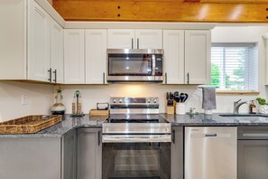A modern kitchen with white cabinets, a stainless steel microwave, an oven, and a dishwasher.