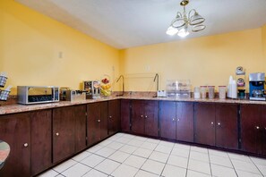 A kitchen with dark wooden cabinets, a microwave, a toaster, and a coffee maker.