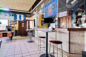 Un área de bar con mesa de billar, taburetes y mostrador.