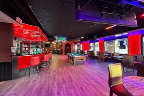 Ein Billardraum mit Pooltisch, roter Bar und Sitzgelegenheiten.