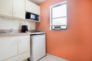Eine kompakte Küche mit Mikrowelle, Kaffeemaschine und kleinem Kühlschrank.