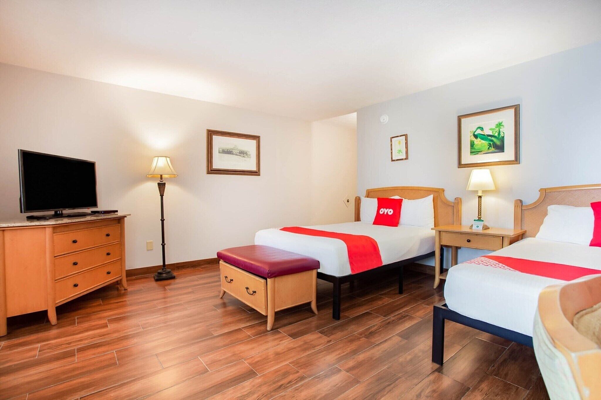 Ein Hotelzimmer mit zwei Betten, einem Fernseher, einem Schreibtisch und einer Lampe.