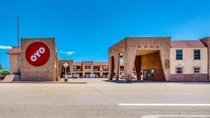 A building with a prominent red circular logo, a parking lot, and a clear blue sky.
