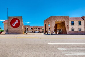 A building with a prominent red circular logo, a parking lot, and a clear blue sky.