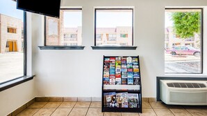 Ein Zimmer mit drei Fenstern, einem Wandtelevisor, einer Wandklimaanlage und einer Auswahl an Reisemagazinen.