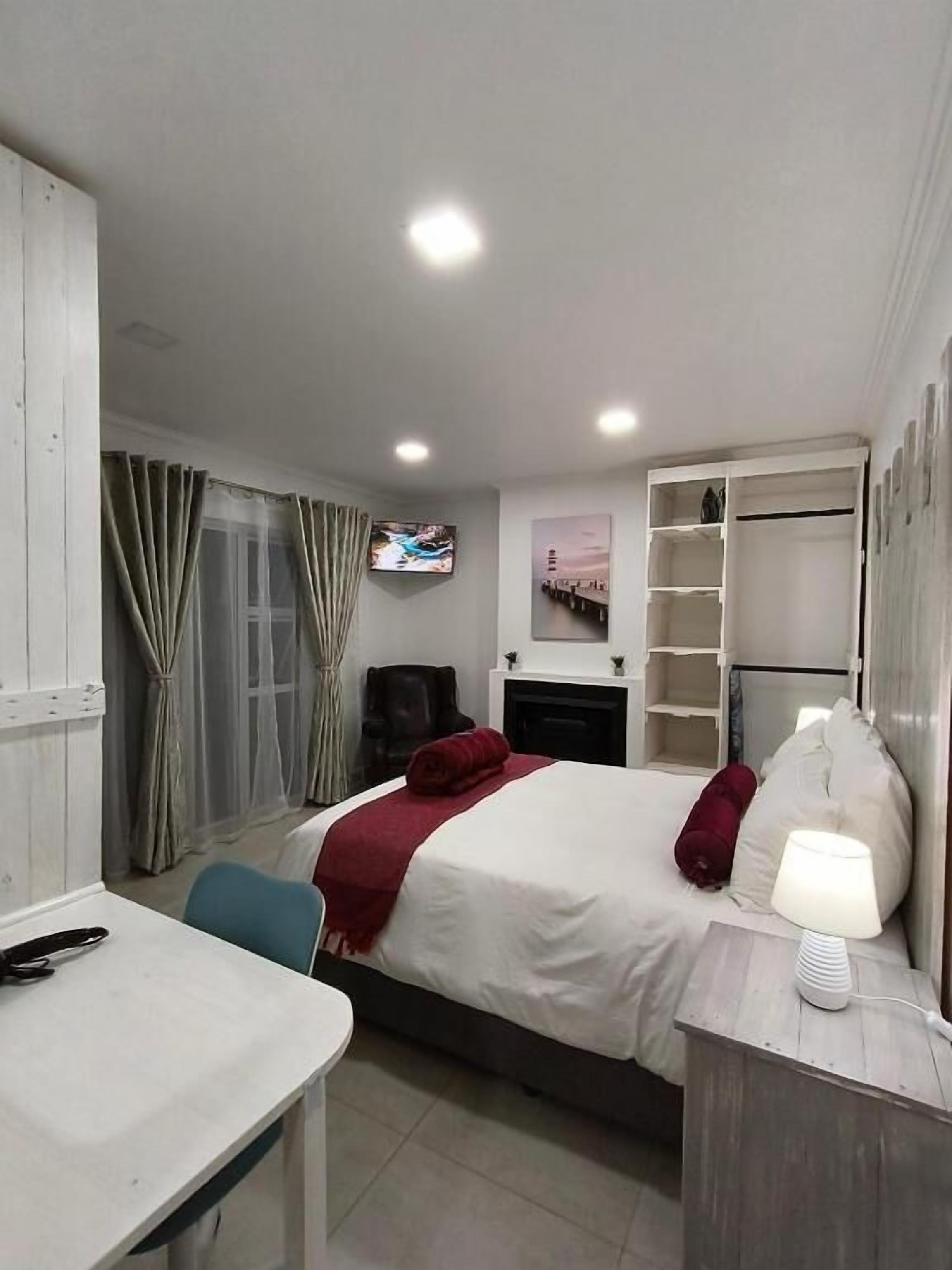 Une chambre d’hôtel comprenant un lit, une table de chevet, une télévision et un bureau avec une chaise.