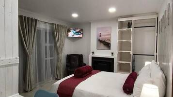 Une chambre d’hôtel comprenant un lit, une table de chevet, une télévision et un bureau avec une chaise.