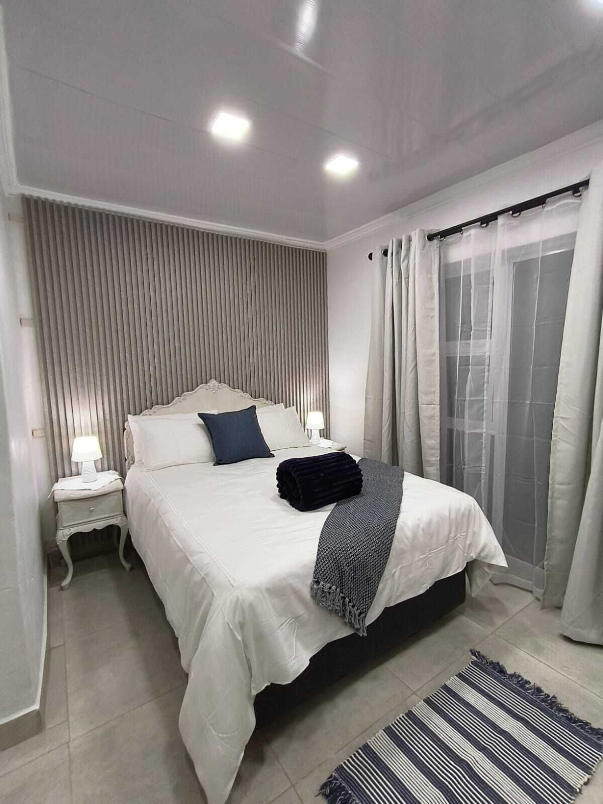 Een slaapkamer met een bed, nachtkastje en een raam met gordijnen.