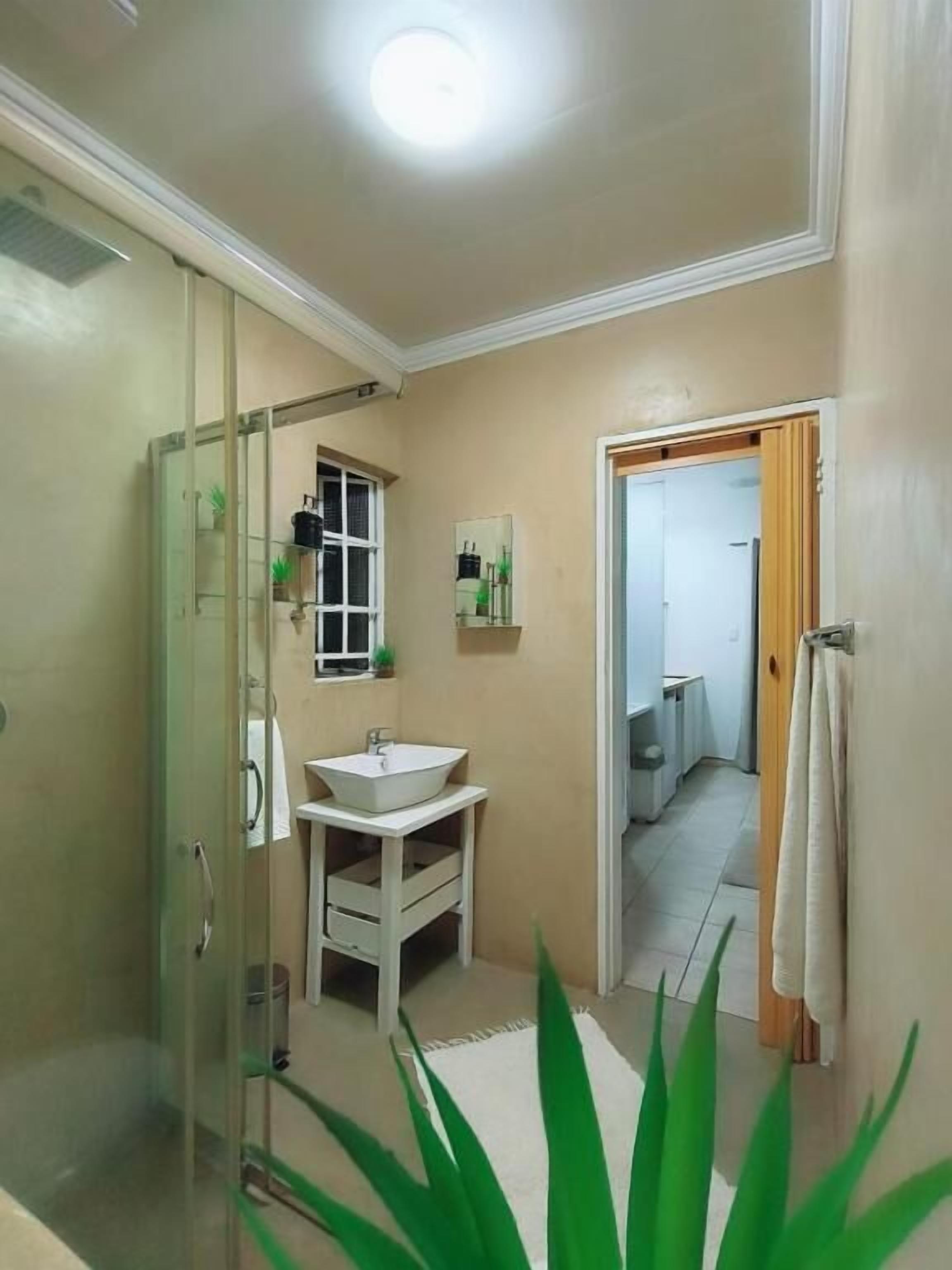 Casa de banho com cabine de chuveiro em vidro, lavatório branco e espelho.