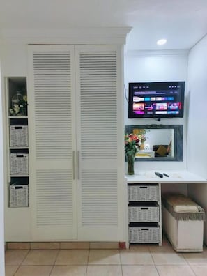 A room with a white wardrobe, a flat-screen TV mounted above a desk, and storage baskets. - Wag-n-Bietjie Accommodation (Centurion)