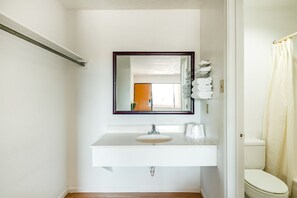 A bathroom with a white sink, a mirror, and a toilet.