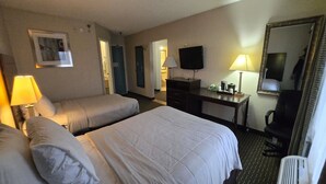 Ett hotellrum med två sängar, ett skrivbord, en tv och en spegel.