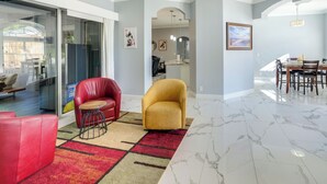 Een moderne woonkamer met een rode bank, een gele fauteuil en een eethoek met een tafel en stoelen.