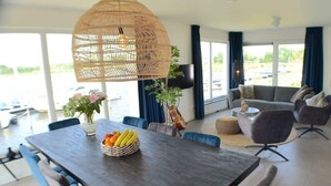 Un espace repas moderne avec une table en bois foncé, des chaises recouvertes d’un tissu bleu et un luminaire suspendu en fibres tressées.
