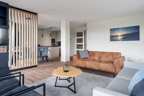 A modern living room with a sofa, coffee table, and a TV. - Chic Dune View Stay in Breskens (Breskens)