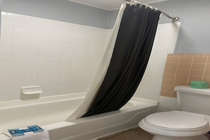 A bathroom with a bathtub, toilet, and a shower curtain.