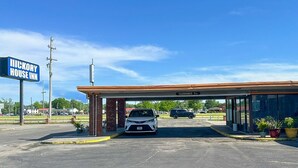 A Hickory House Inn with a clear sky, a covered parking area, and a visible car.