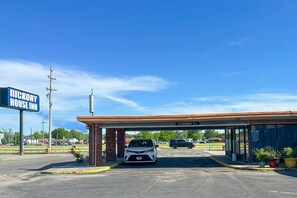 Un Hickory House Inn con cielo despejado, zona de estacionamiento techada y un coche visible.