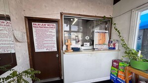 A Palm Leaf Motel reception area with a check-in counter, a door with a sign, and vending machines.