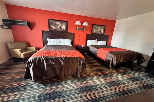 Une chambre d’hôtel avec deux lits, une chaise, une table de chevet et deux lampes fixées au mur.