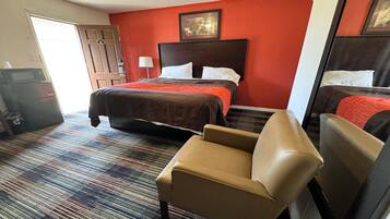 Ein Hotelzimmer mit einem großen Bett, einem kleineren Bett, einer Couch, einem Schreibtisch und einer Tür.